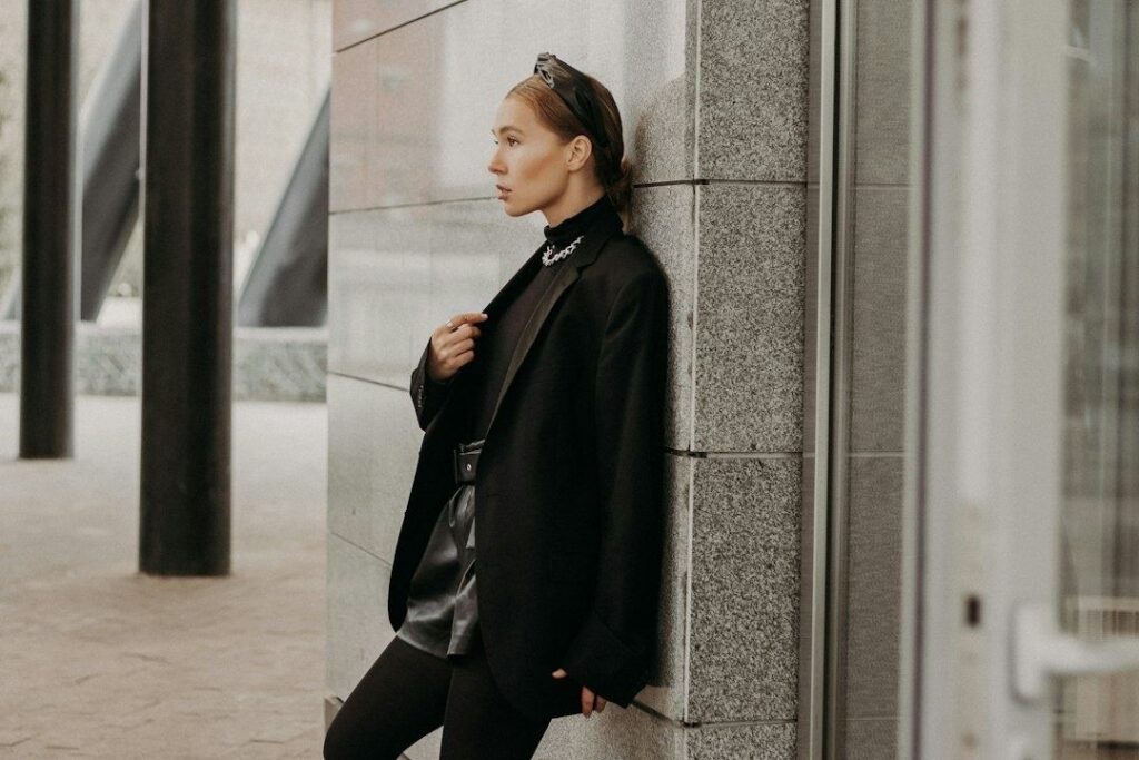 Stilbevidst kvinde i sort, oversized blazer foran en moderne bygning