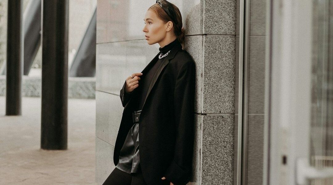 Stilbevidst kvinde i sort, oversized blazer foran en moderne bygning