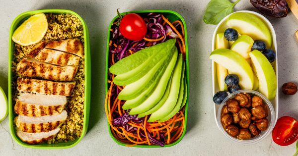 Tre farverige madpakker med grillet kylling, avocado og frisk frugt.
